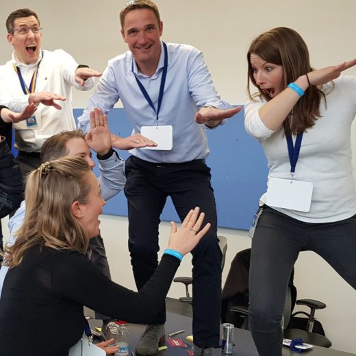 business_coaching Teamworkshop mit Julia Jauß: Teilnehmer stehen auf dem Tisch, lachen und interagieren spielerisch während einer Gruppenübung
